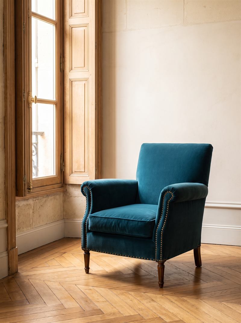 Fauteuil club des années 1950 regarni en velours bleu canard avec clous laiton, dans un appartement bordelais au parquet en point de Hongrie